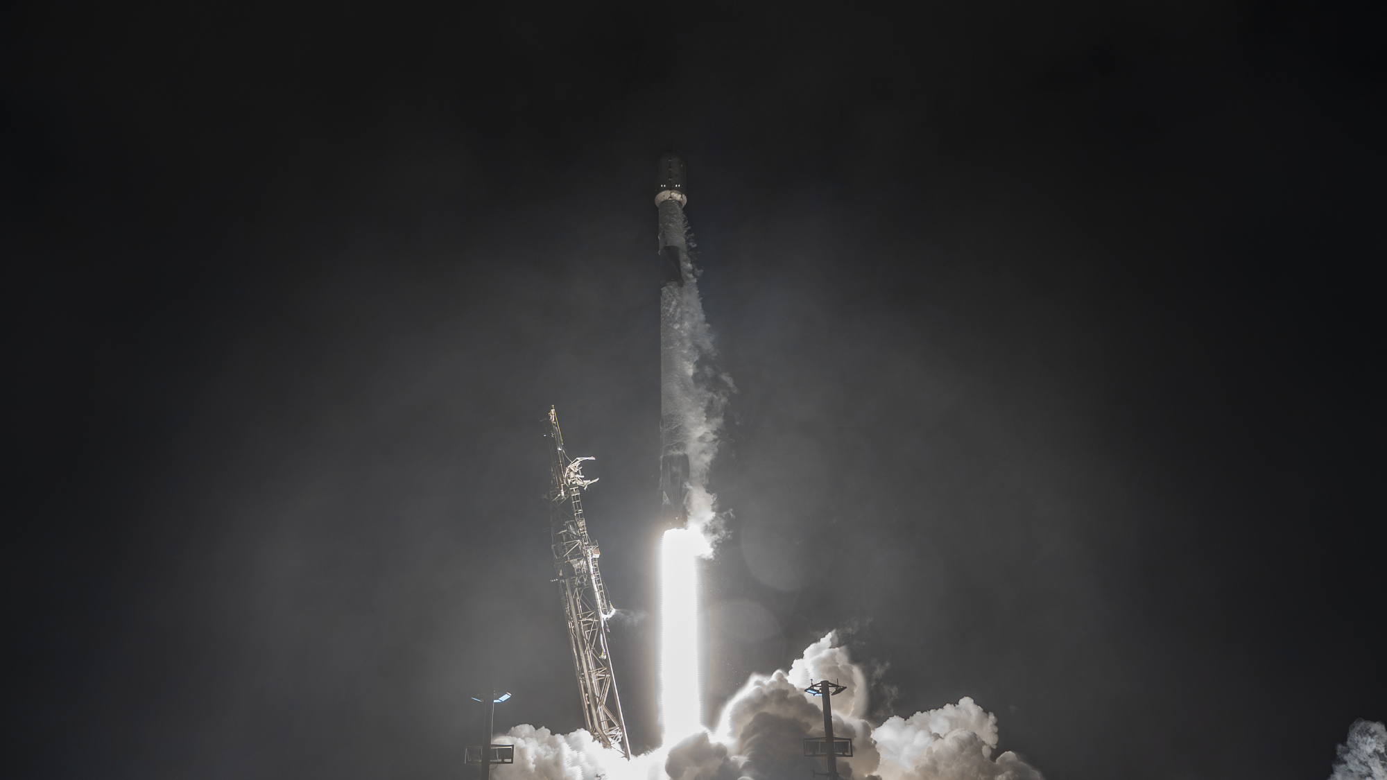 A white rocket blasts off in the dark of night.