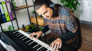 Man playing digital piano with headphones on