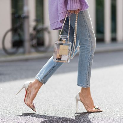 solid perfumes-street style woman with lilac jumper, heels and chanel perfume bottle handbag