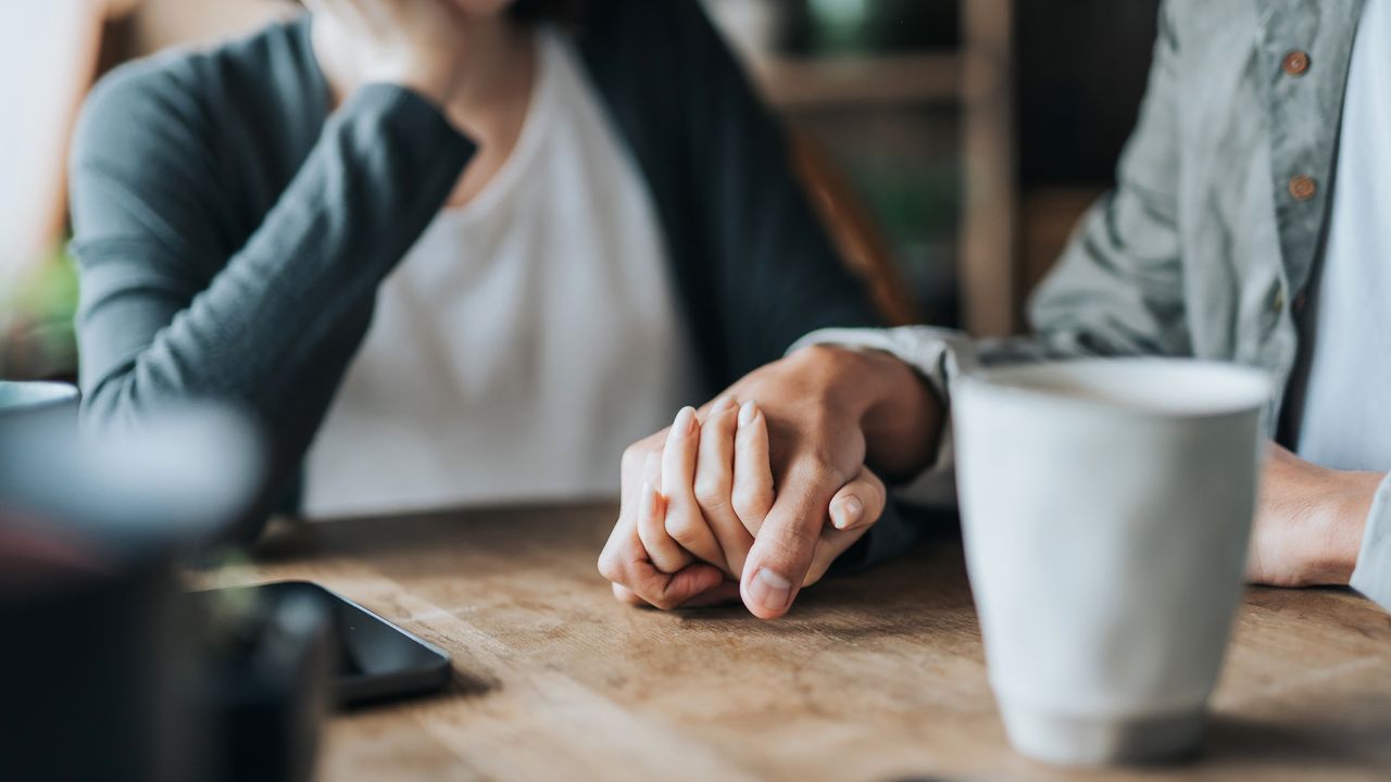 A man and a woman hold hands on top of a dining table.