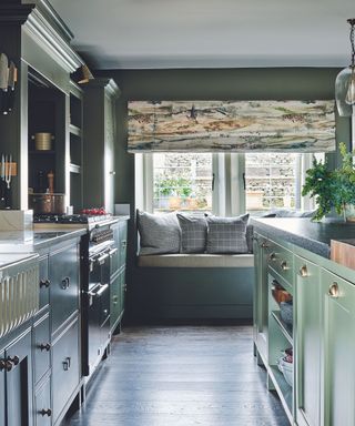 A green kitchen with a seating area and large windows