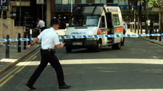 A policeman extends a cordon near Tavistock Square following the London bombings.