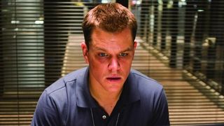 Matt Damon sits in a police precinct office in The Departed