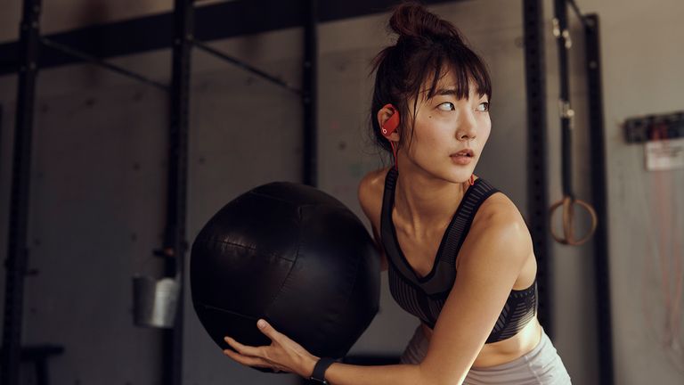 Beats Powerbeats Review: Pictured here, young woman using a slm ball in a gym
