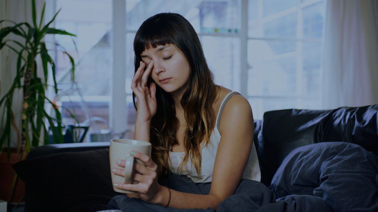 A person sitting on a sofa looking tired and depressed