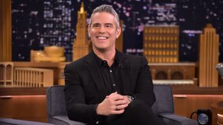 Andy Cohen smiles as he sits on one of the armchairs while visiting "The Tonight Show Starring Jimmy Fallon" on December 5, 2018 in New York City.