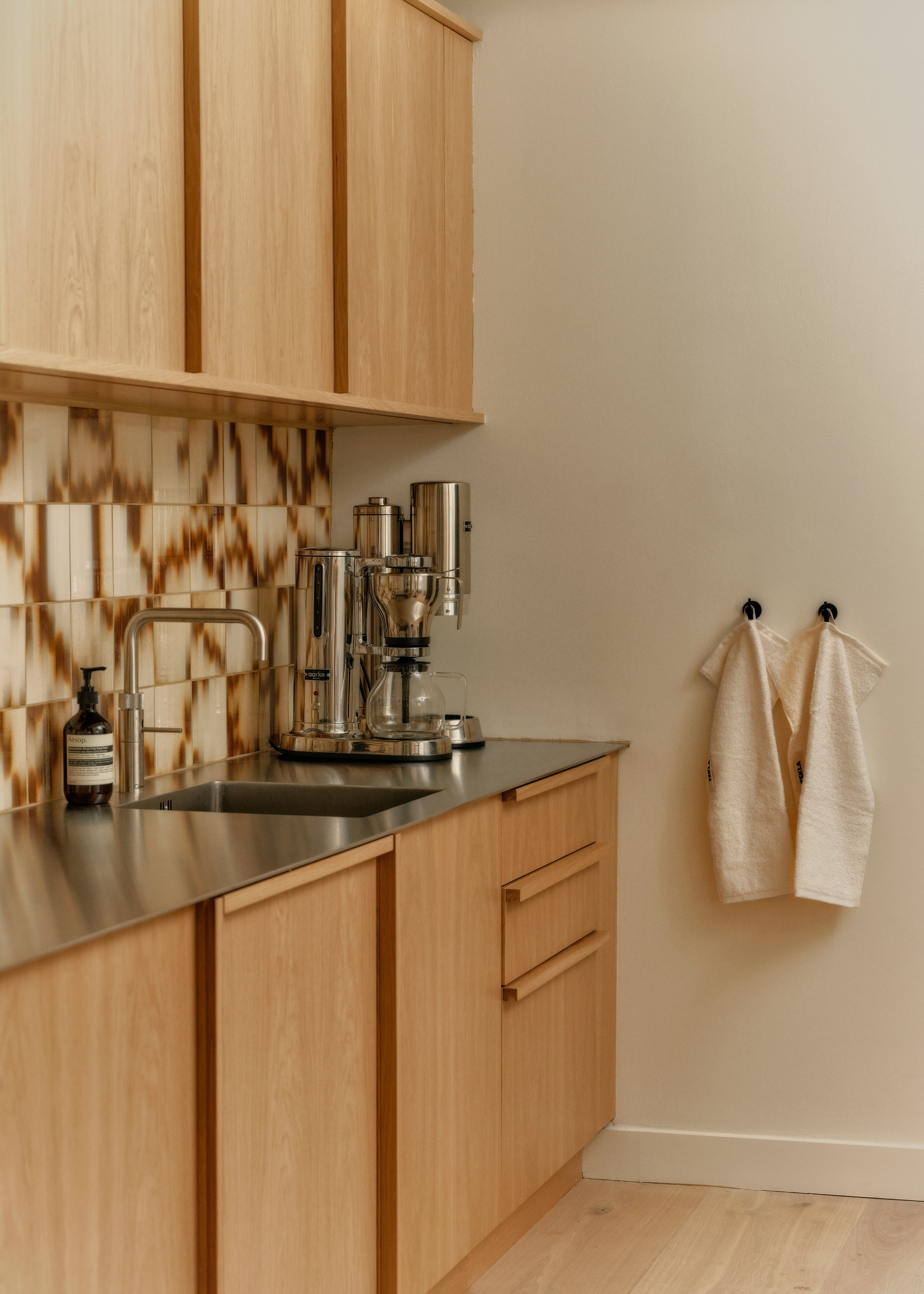 brown marble palet tile splashback in a wooden kitchen with stainless steel worktops