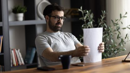 A man tidies up a pile of paperwork at his desk.