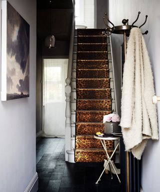 Small hallway ideas with a leopard print carpet running up the stairs, black flooring and pale lilac walls.
