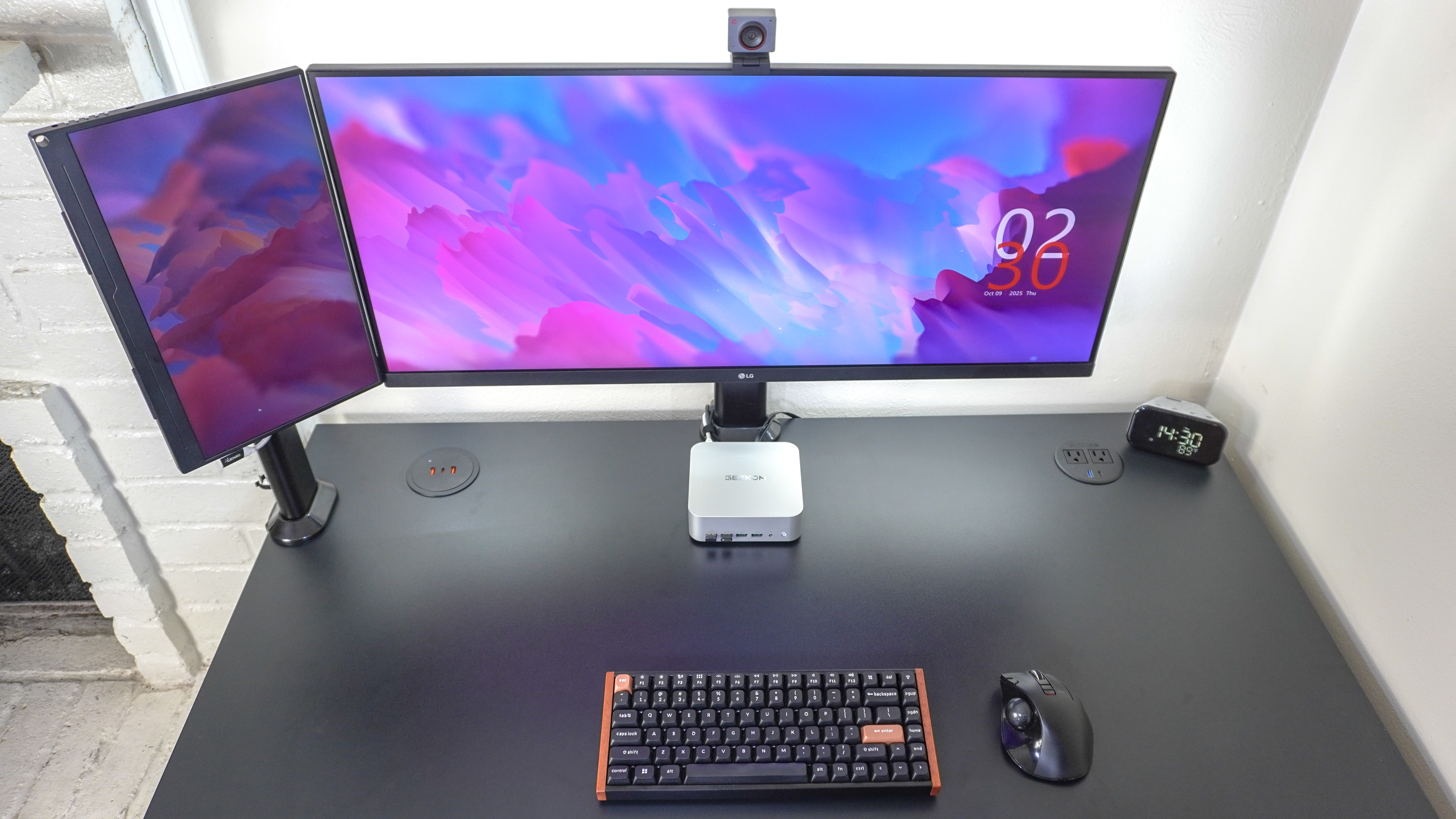 An overhead view of a desk setup with a portable monitor mounted next to an ultrawide display