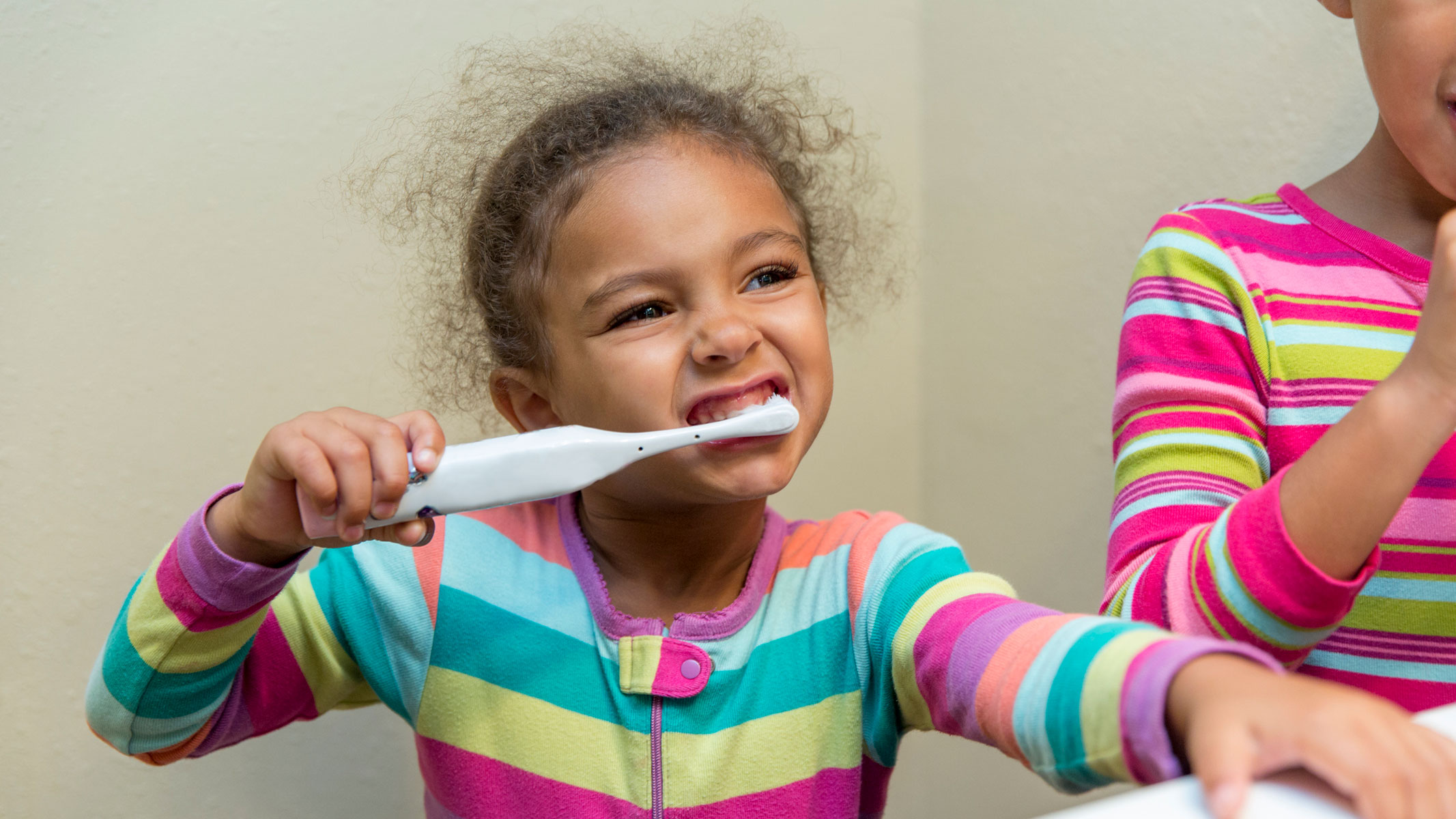 A picture of a little girl brushing her teeth with an electric toothbrush
