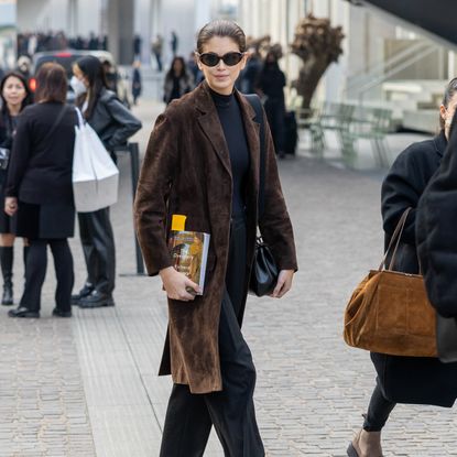 Kaia Gerber wearing brown suede coat with black mock neck top