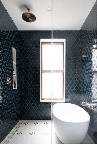 A bathroom with dark wall tiles and light floor tiles