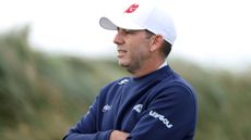 Sergio Garcia wearing a navy blue sweater and white cap with his arms crossed