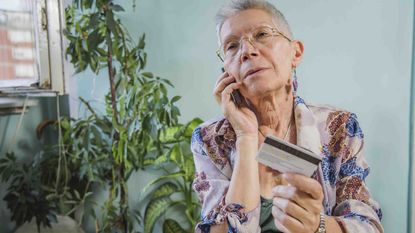 Photo of an older woman talking on the phone and holding her credit card