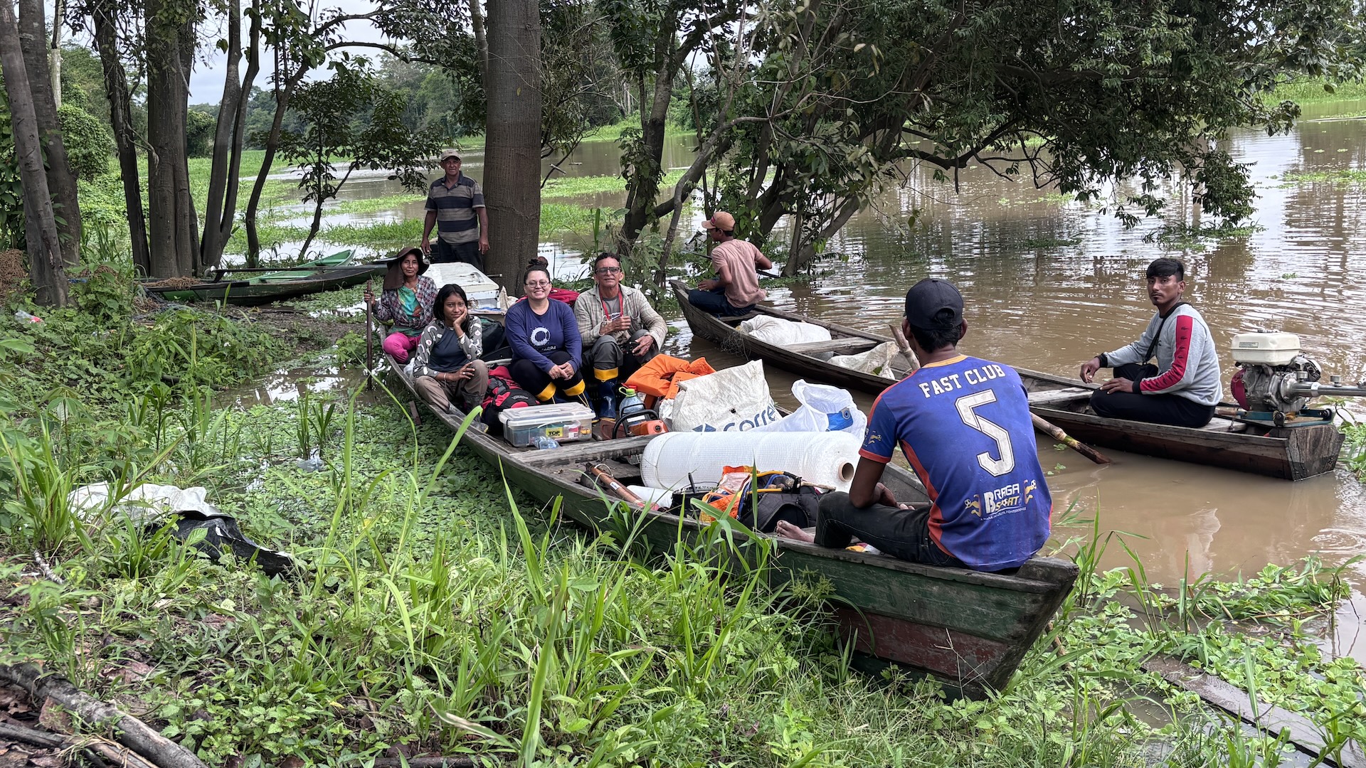a group of people paddle boats filled with equipment through the rainforest