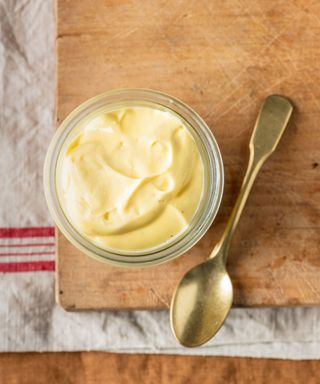 Mayonnaise in bowl with spoon on chopping board