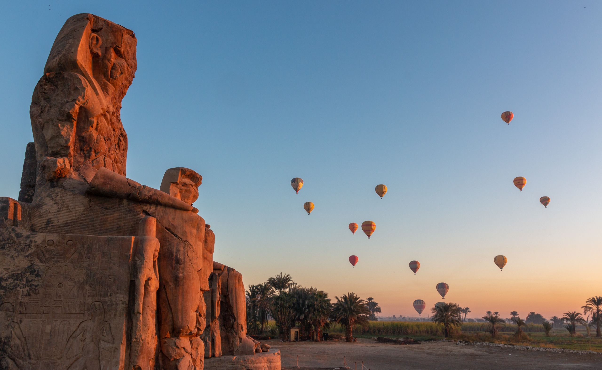 Colossi of Memnon at dawn with hot air balloons in the sky, Luxor, Nile Valley, Egypt