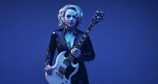 Samantha Fish, lit up in blue, photographed with her Gibson SG.