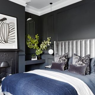 bedroom with black wall and bed with designed cushion