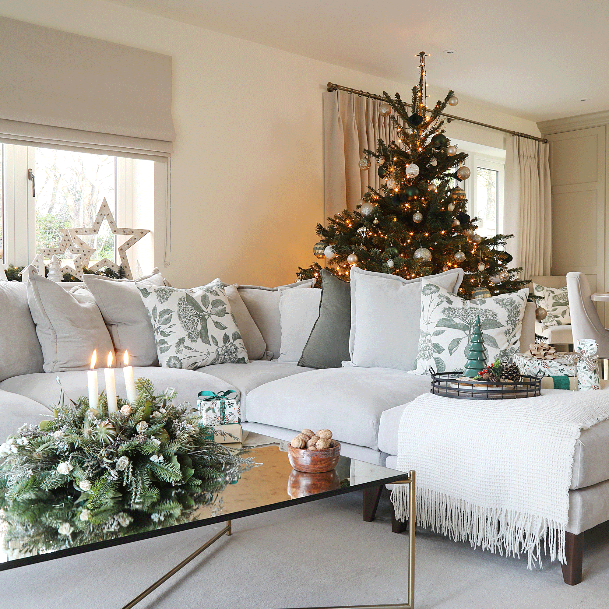 a neutral open plan living room with a christmas tree and corner sofa with lots of festive decorations