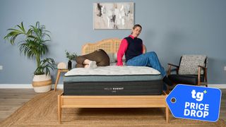 Two Tom's Guide testers on the Helix Sunset Luxe mattress in a bedroom, with a Tom's Guide badge overlaid saying "PRICE DROP"