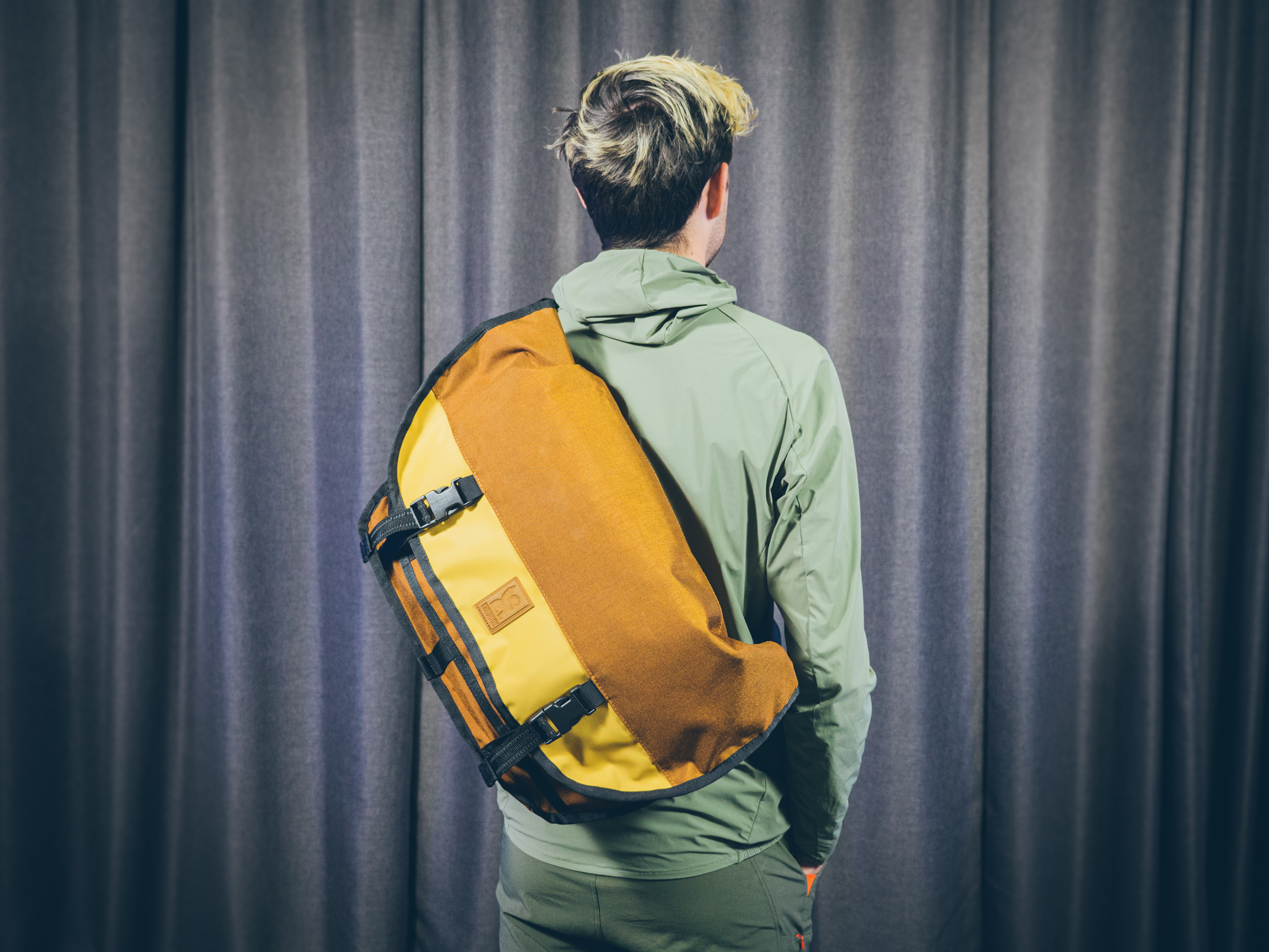 Will Jones, wearing one of the best backpacks for cycling, stands in front of a wall