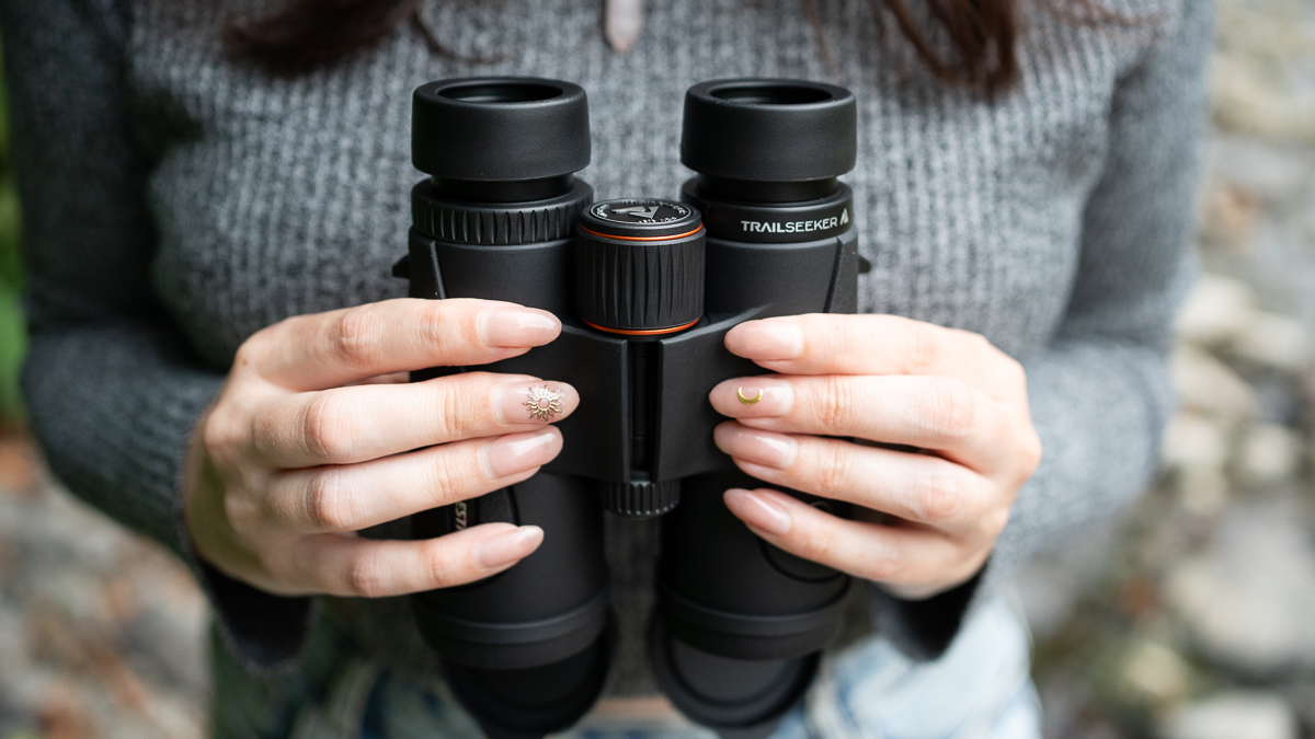 woman using the Celestron TrailSeeker 10x42 by a river