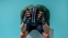 Male cyclist leaning forward, holding his head in his hands