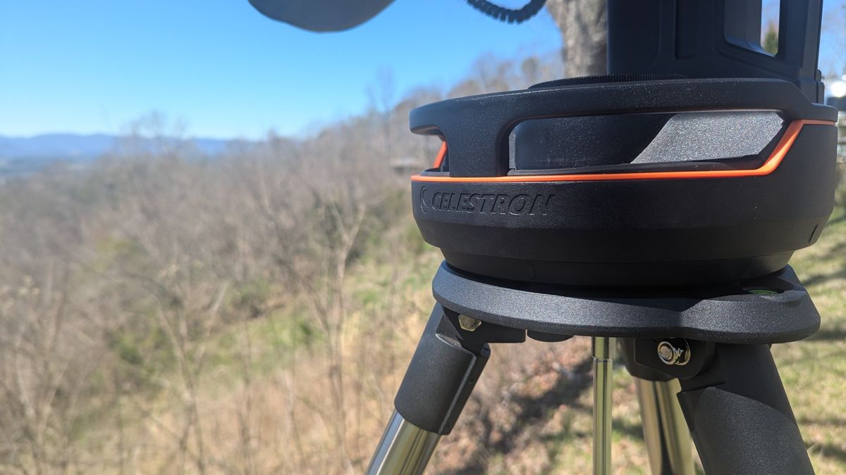 a white telescope on a grassy mountaintop under a clear blue sky