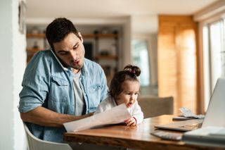 A man and his child on a desk at their house as he tries to work from home