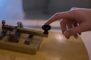 Finger pressing a Morse code receiver