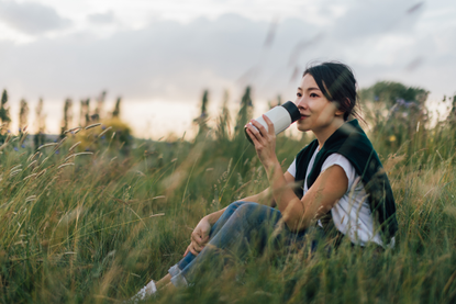 Woman sitting in a field, suffering with hay fever symptoms