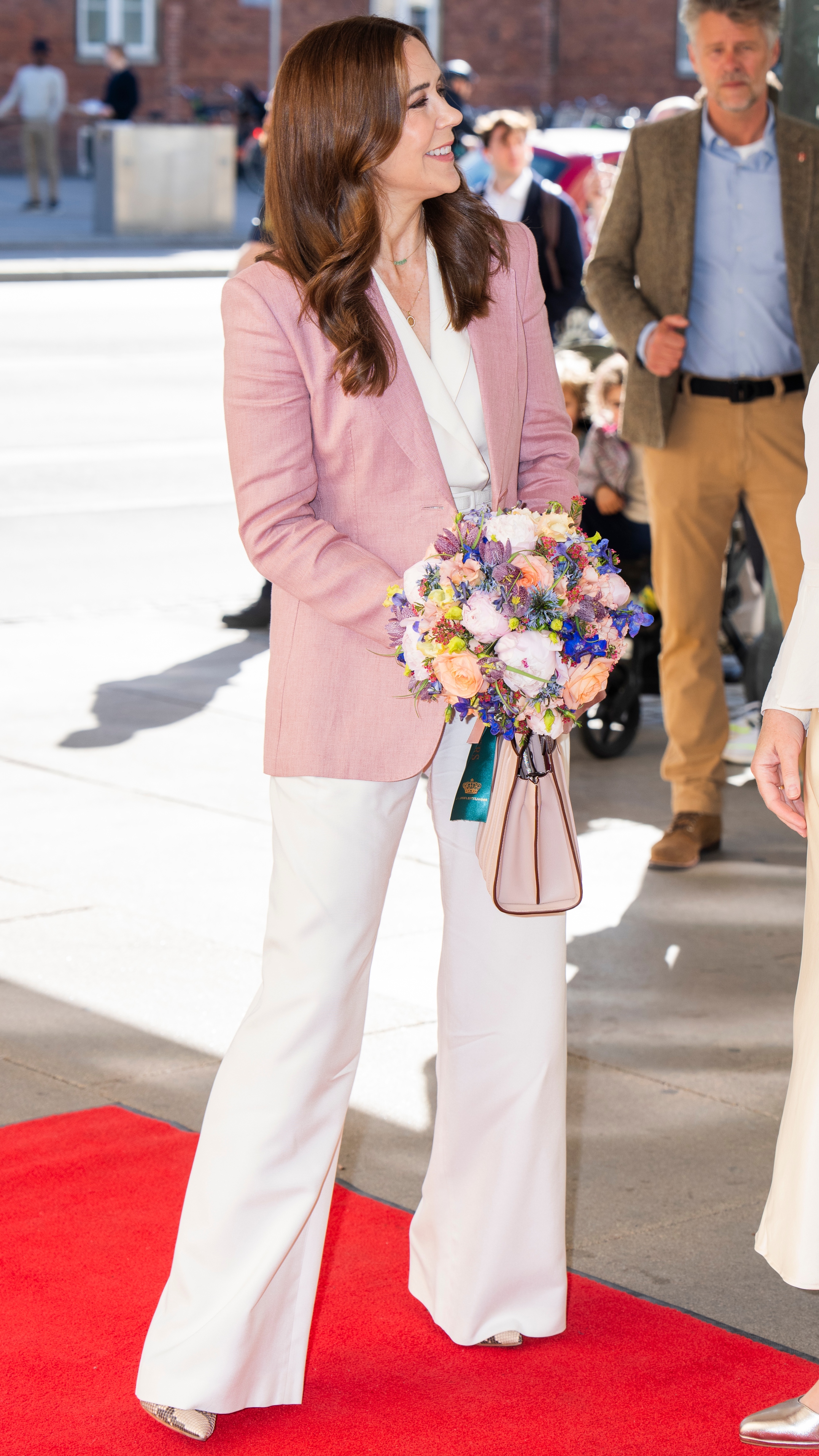 Queen Mary of Denmark stands, holding flowers, as she arrives at the Royal Danish Academy of Music on May 6, 2025