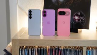 A size comparison between the Samsung Galaxy S25 (left), iPhone 16 (middle), and Google Pixel 9 (right) on a record table.