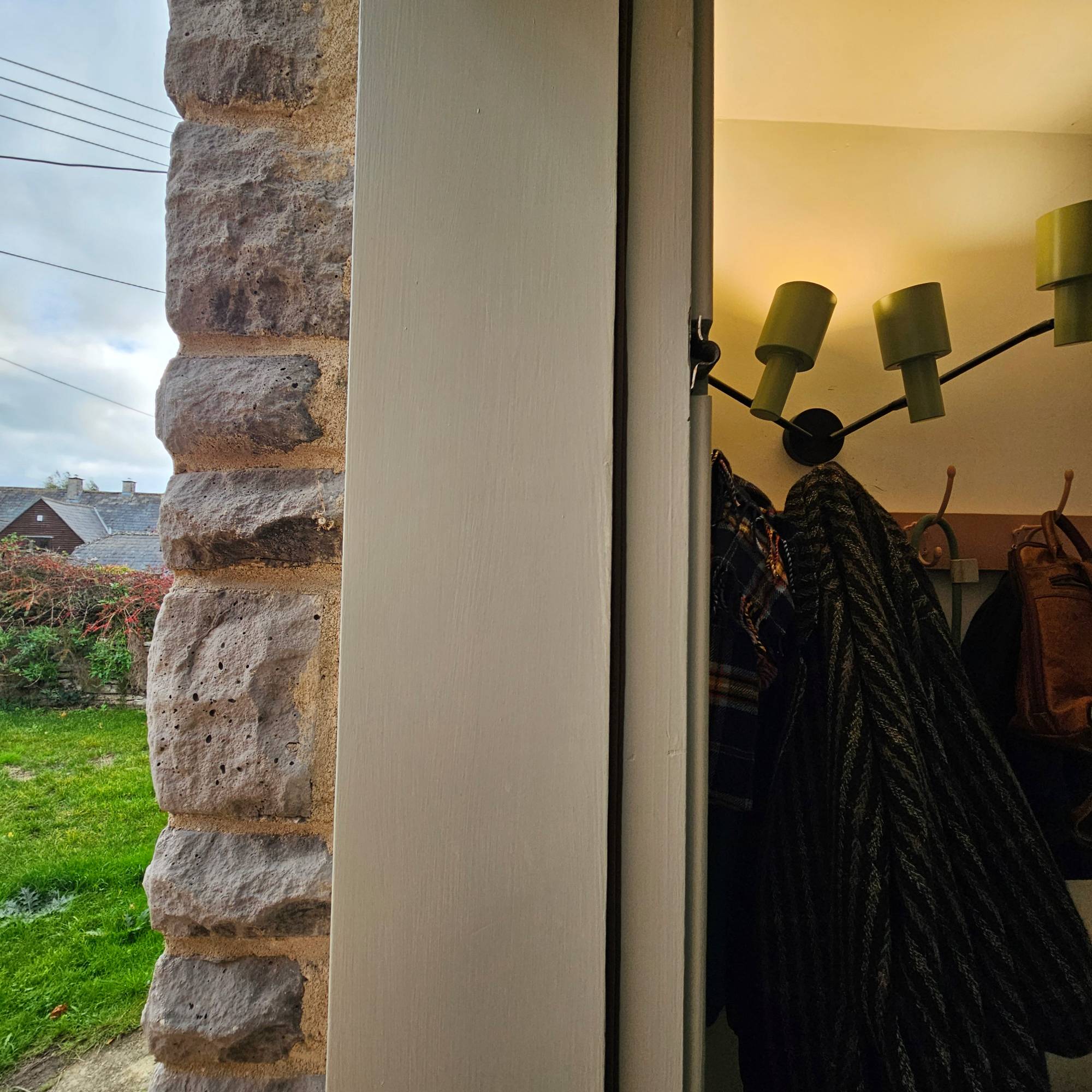 pale green wooden door frame with draught proofing tape and coat hooks