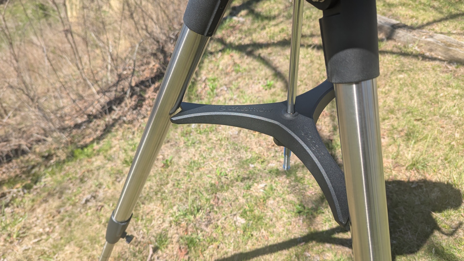a white telescope on a grassy mountaintop under a clear blue sky