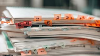 A stack of notebooks with orange sticky tabs with numbers poke out between pages