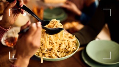 Woman serving from a large bowl of fettuccine pasta onto plates, an example of what to eat when reverse dieting