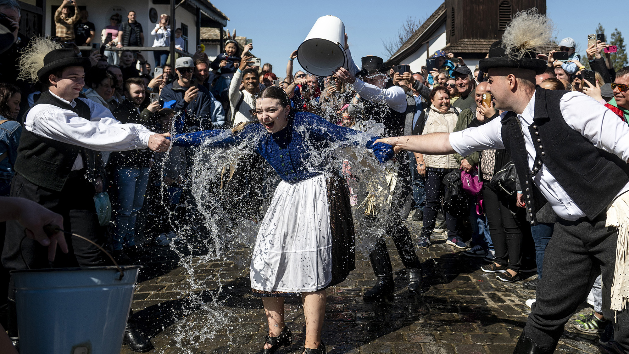 Young men douse young women with buckets of cold water during the Easter folk festival in the ethnographic village of Holloko, Hungary