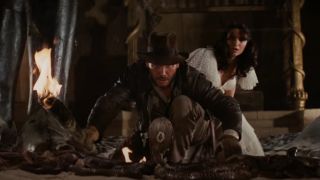 Indiana Jones and Marion Ravenwood surrounded by snakes and faced in front of a cobra