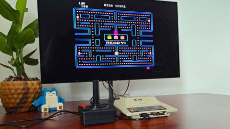 Atari 400 Mini on woodgrain desk connected to Dough Spectrum Black OLED monitor and Pac-Man on screen.