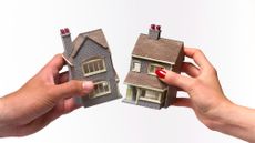 Two hands, one belonging to a man and one to a woman, pulling at and breaking a toy house in half