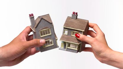 Two hands, one belonging to a man and one to a woman, pulling at and breaking a toy house in half