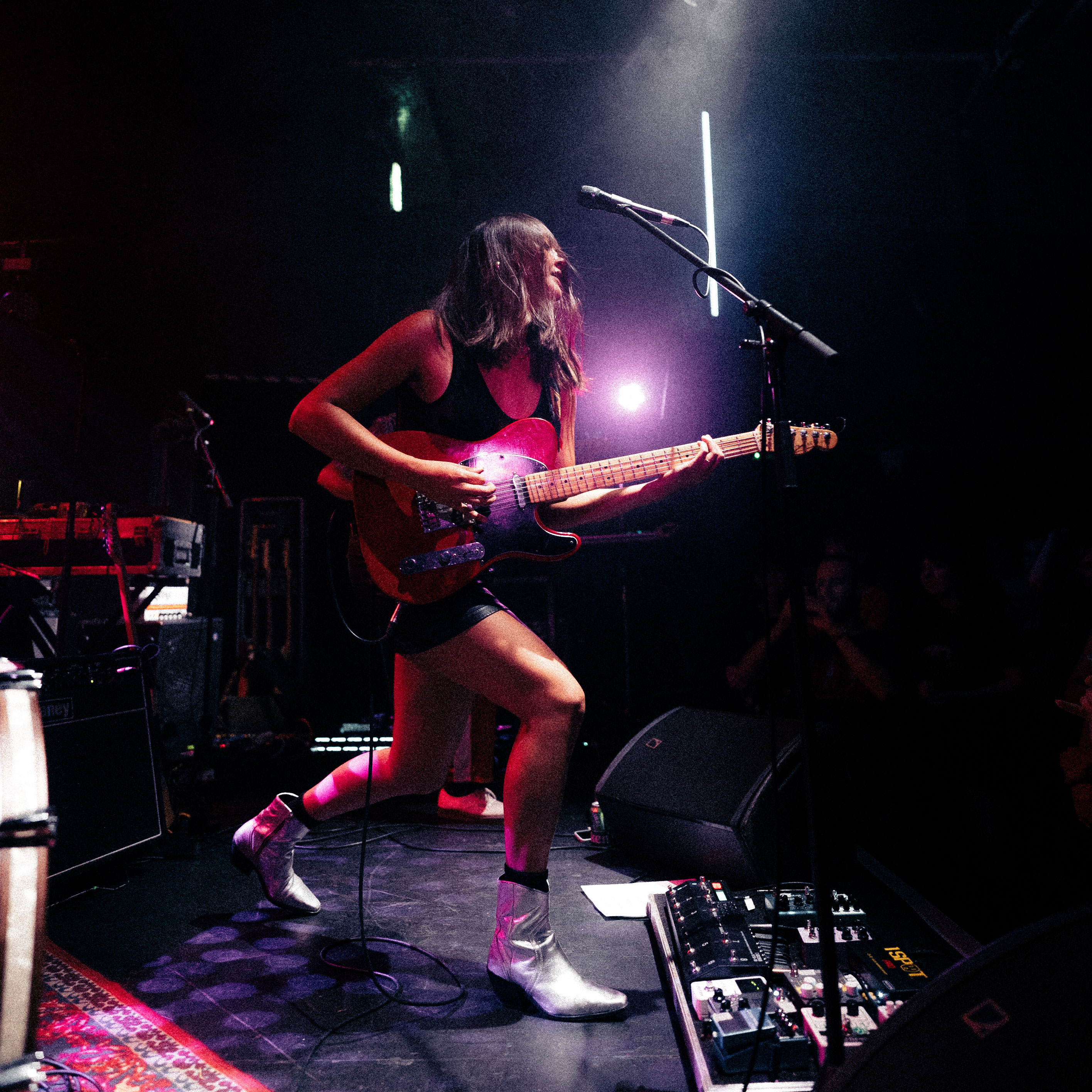 Tina Maynard of UK rock band Masca a red Telecaster at a live show, her pedalboard is visible on the stage below