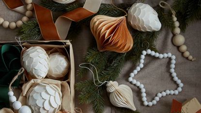 Paper and beaded christmas decorations laying on a wooden table, viewed from the top