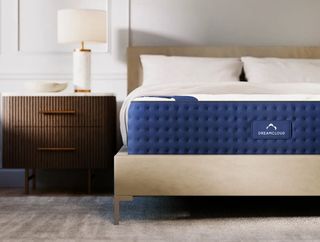 DreamCloud memory foam mattress on a wooden bed frame in a neutral bedroom