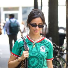 Camila Cabello wearing a green jersey shirt, black skirt, black strappy sandals, and a leopard print skirt