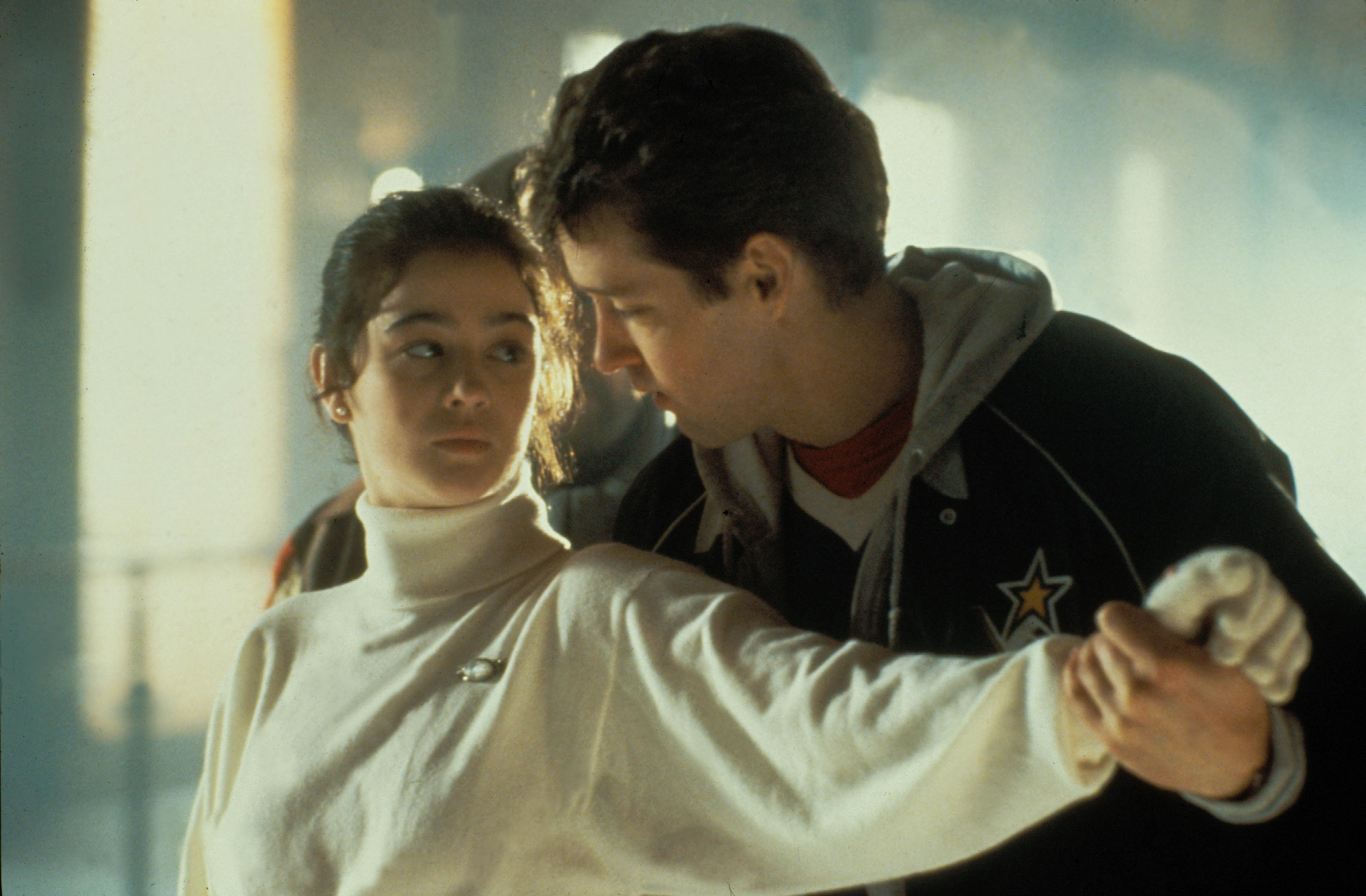 Moira Kelly wearing a turle neck and being guided by a man on an ice skating rink in 'The Cutting Edge'