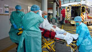 Health workers unload a patient from an ambulance outside a hospital